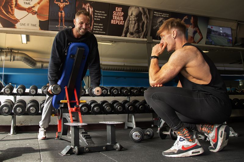 Vincent van Haren begeleidt een klant bij de dumbbells in de gym